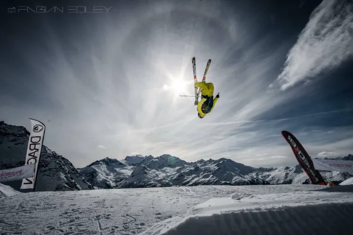 Man skiing in yellow gear doing a back flip